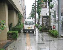 歩道の上に点字ブロックをまたぐようにして車が停まっています。歩道が狭くなっています。